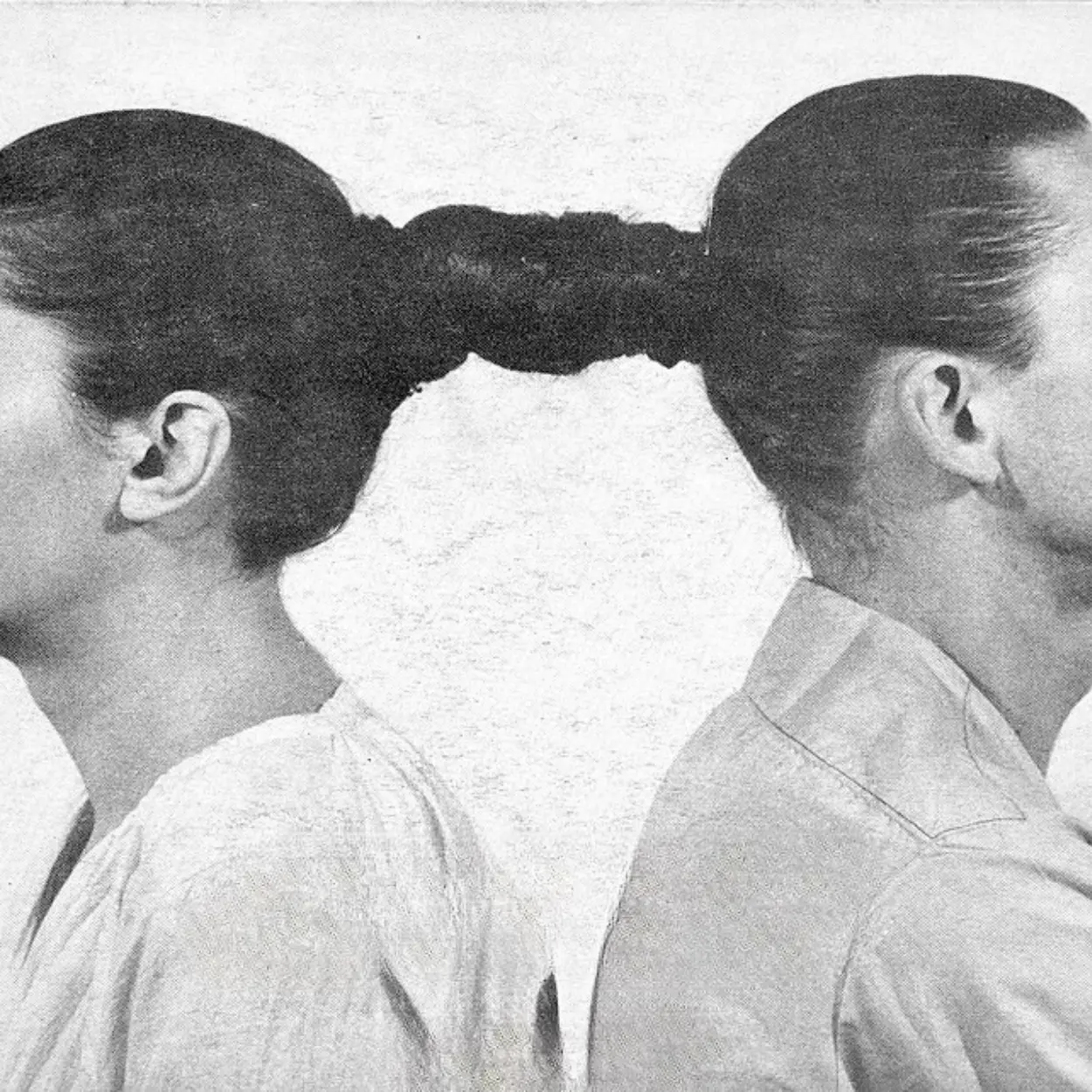 Black and white photograph of two figures joined by braided hair